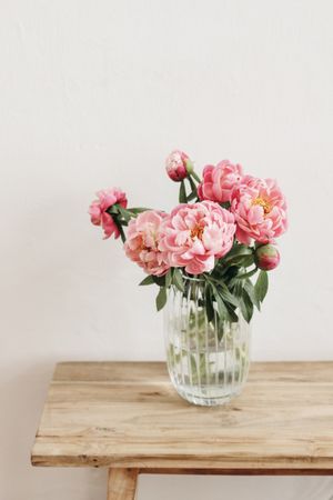Elegant vase of pink flowers on wooden table