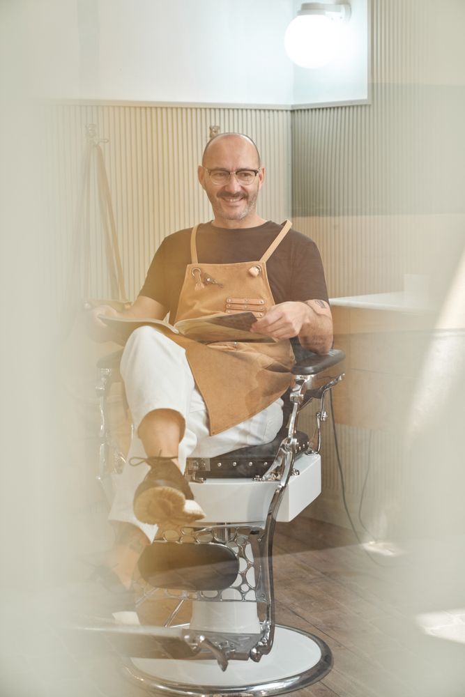 Stylish barber reading book in barbershop