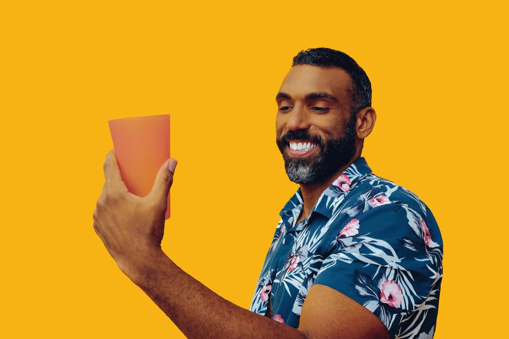 Male smiling at his drink in a orange cup with copy space