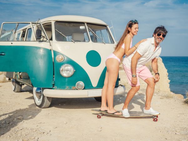 Man and woman on a longboard near trailer