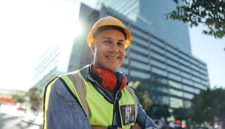 Contractor standing in front of high rise buildings in safety clothes