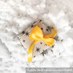 Present wrapped in yellow bow on snow 5ra830