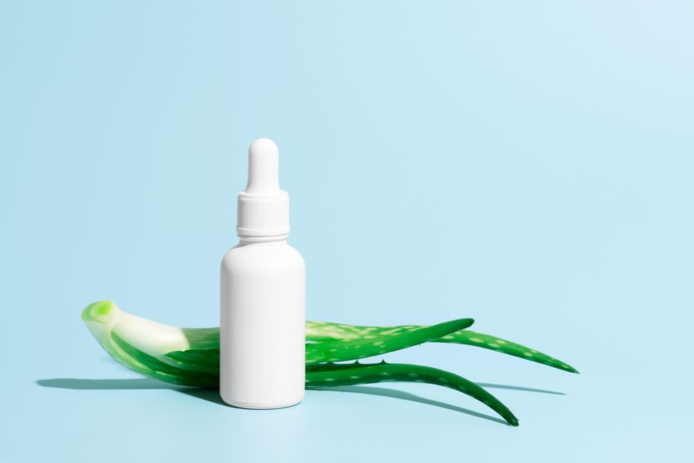 Side view of aloe vera plant and cosmetic bottle