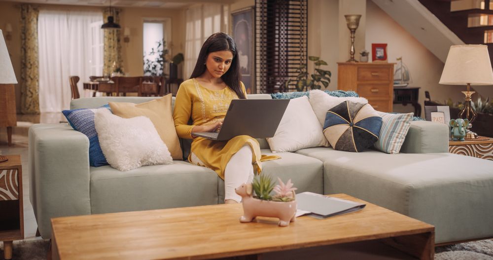 Woman Works Remotely From Home, Seated On Sofa With Laptop. Productive and Efficient at Virtual Management.