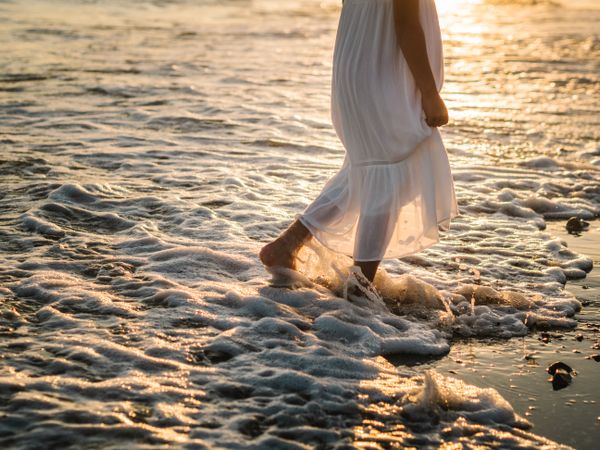 Adorable girl walking on seaside at sunset