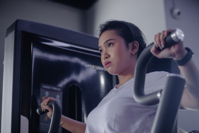 Determined woman exercising on chest press machine indoors gym
