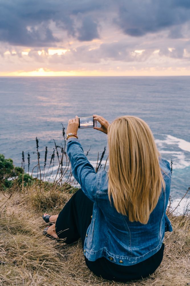 Female tourist taking shot of sea in twilight