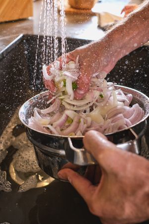 Unrecognizable person rinsing onion under water