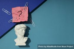 Marble bust of David with crumpled pink post it note with question mark and paper clips, copy space 5om68b