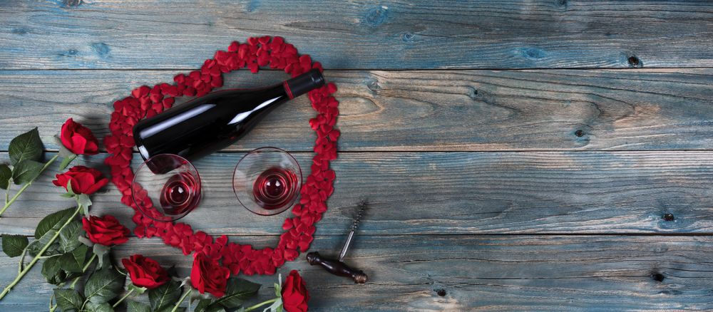 Valentine’s day with large heart outline and wine on blue wood
