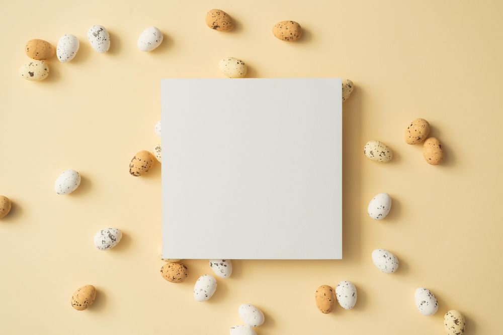 Easter eggs on pastel yellow background with paper card note