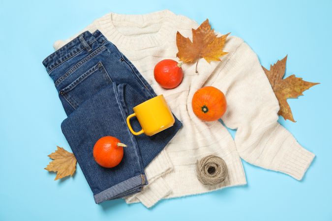 Composition with pumpkins, clothes and leaves on blue background, top view