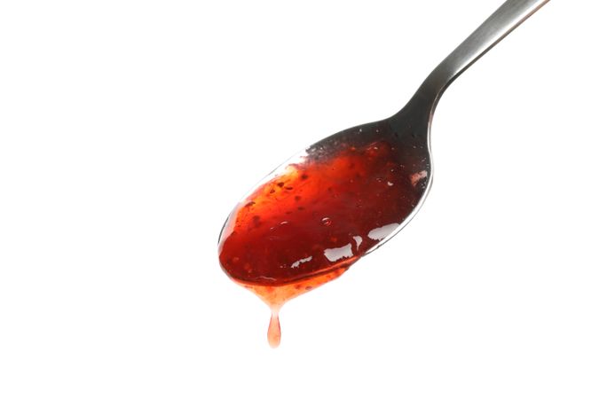 Spoon with strawberry jam isolated on plain background