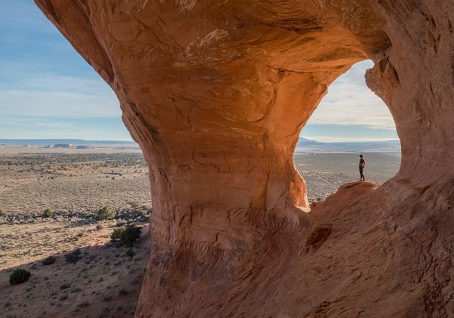 Person standing on beside natural arch