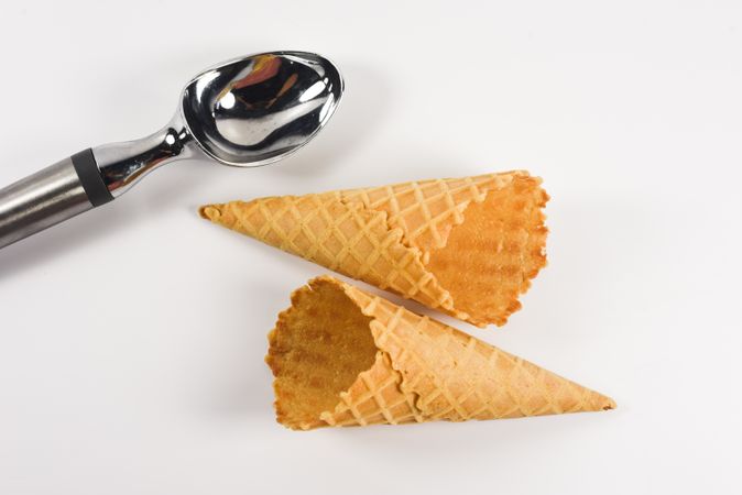 Top view of two waffle cones lying on table with ice cream scoop