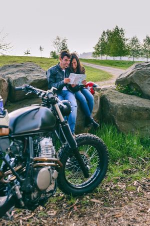 Couple sitting looking at a map with motorcycle