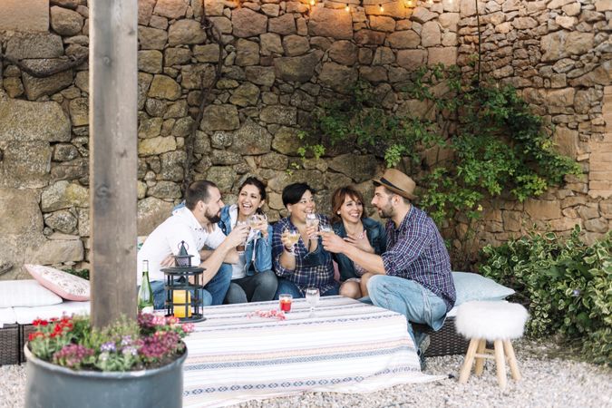 Group of smiling friends sitting together and laughing while enjoying wine at a party