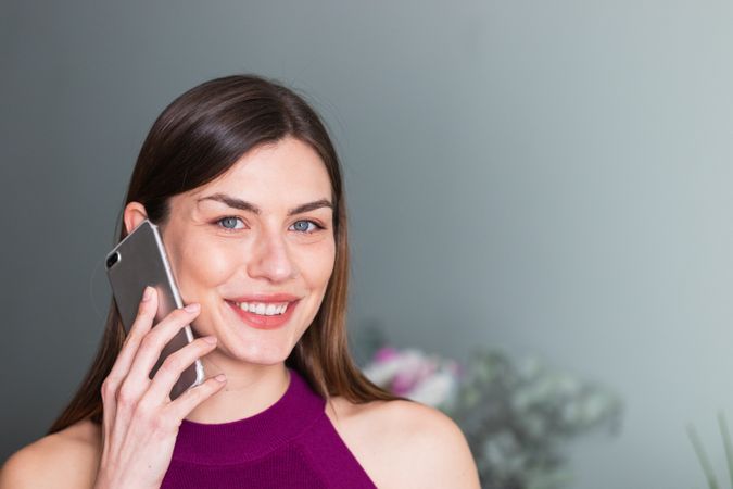 Smiling woman speaking on smartphone at home