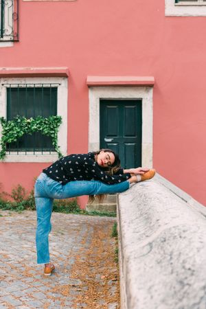 Casual woman dancing on old city street