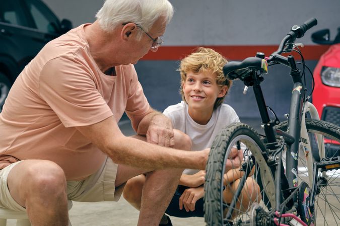 Mature man explaining mechanism of bicycle to grandson