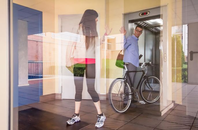 Businessman and sportive woman waving behind glass