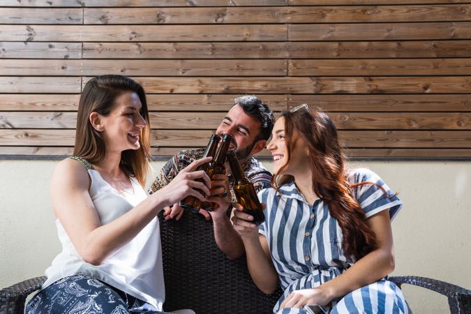 Cheerful friends with beer spending weekend on sofa