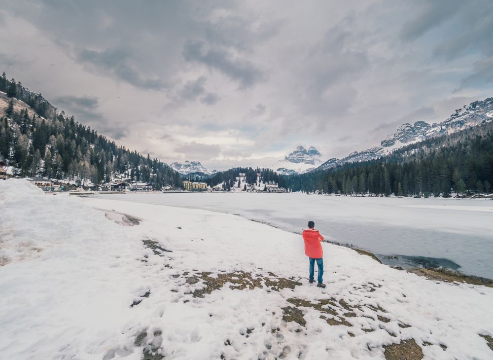 Unrecognizable person standing in snow surrounded by forest and mountains