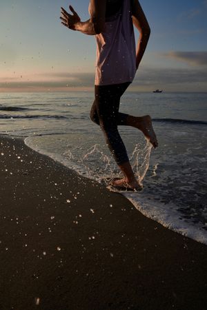 Anonymous runner running on shore at sunset time