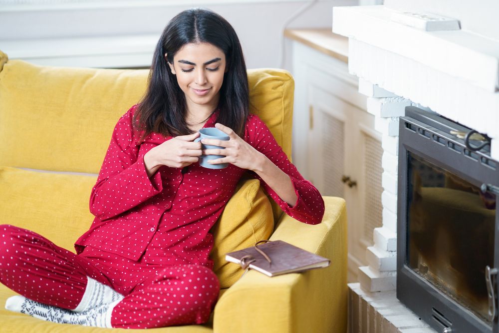 Female sipping tea on yellow sofa at home