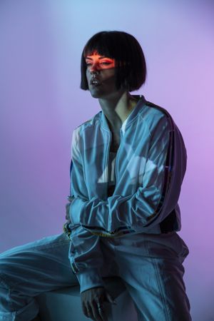 Trendy female sitting on cuboid