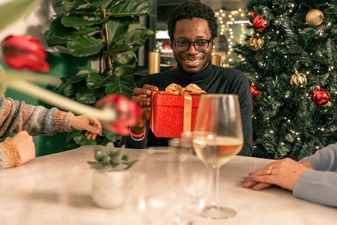 Happy Black man with a joyful expression receiving a gift at a Christmas party