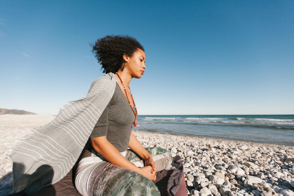 Sportive woman sitting on sandy beach in asana