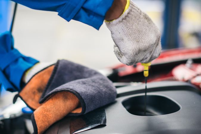 Gloved hand of repairman checking oil of car engine