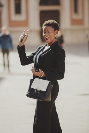 Stylish Black woman with handbag and smartphone on street