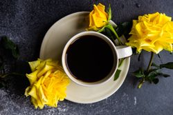 Top view of cup of coffee and yellow roses