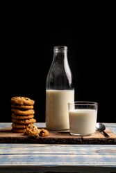 Milk and fresh cookies on board near napkin