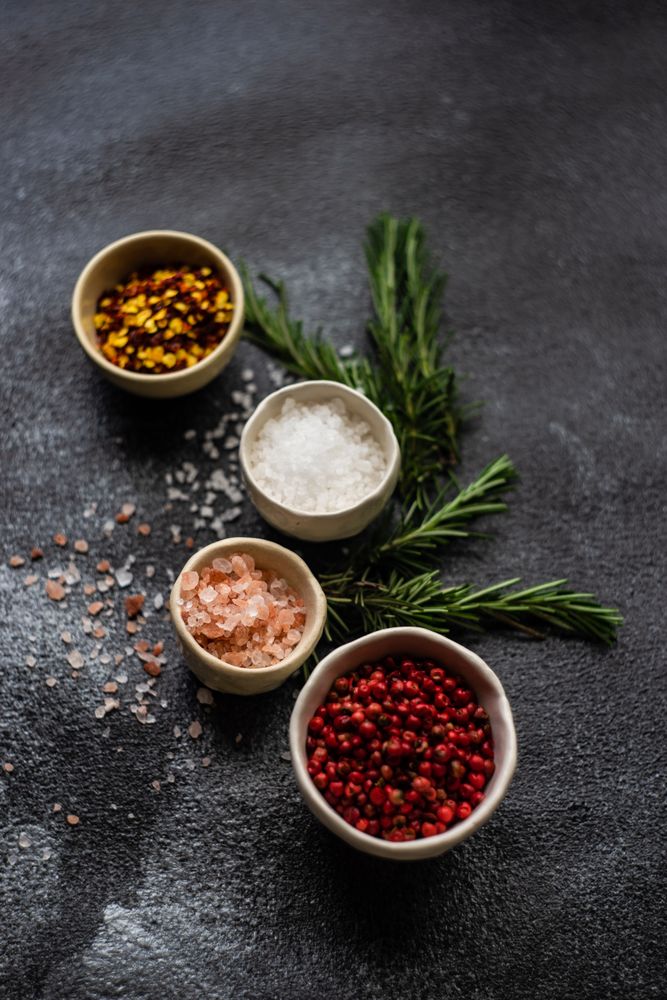 Top view of salt and seasoning bowls and rosemary on kitchen counter