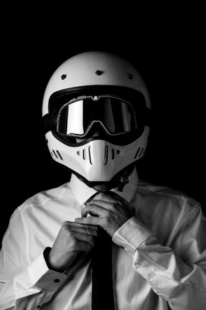 Stylish driver in helmet and eyeglasses adjusting tie in studio