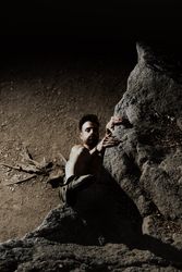 Man practicing rock climbing among large rocks in a forest