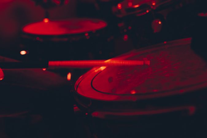 Man with drumsticks playing on drums in redness