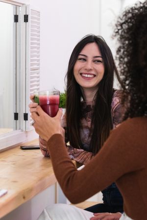 Cheerful diverse women drinking smoothie in bar