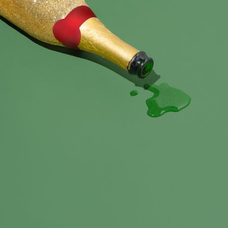 Golden champagne spilled on green background