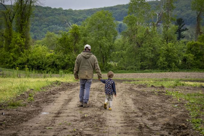 Copake, New York - May 19, 2022: Back of father and child walking through off road path