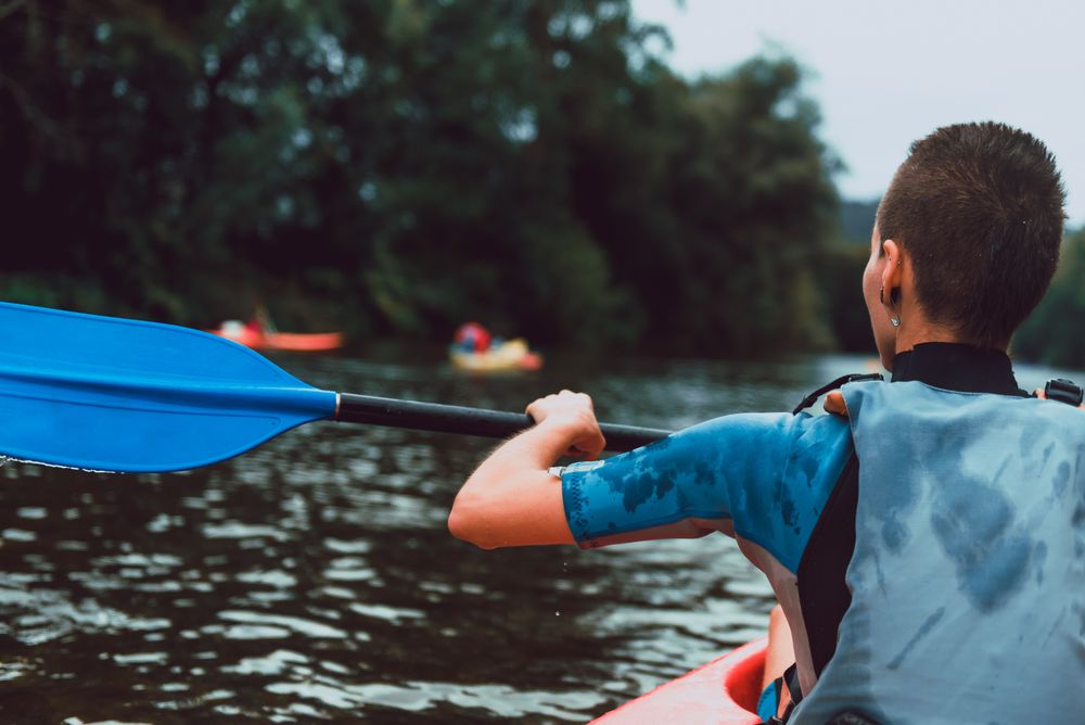 Female kayaking with paddle in raised hands
