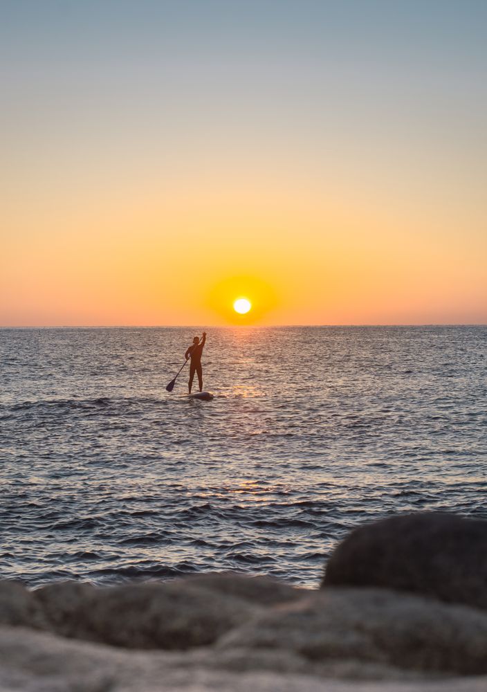 Man practicing paddle surfing with neoprene in a sunrise