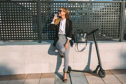 Businesswoman with mobile and her scooter next