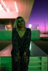adult woman looking at camera against vibrant sky at dusk