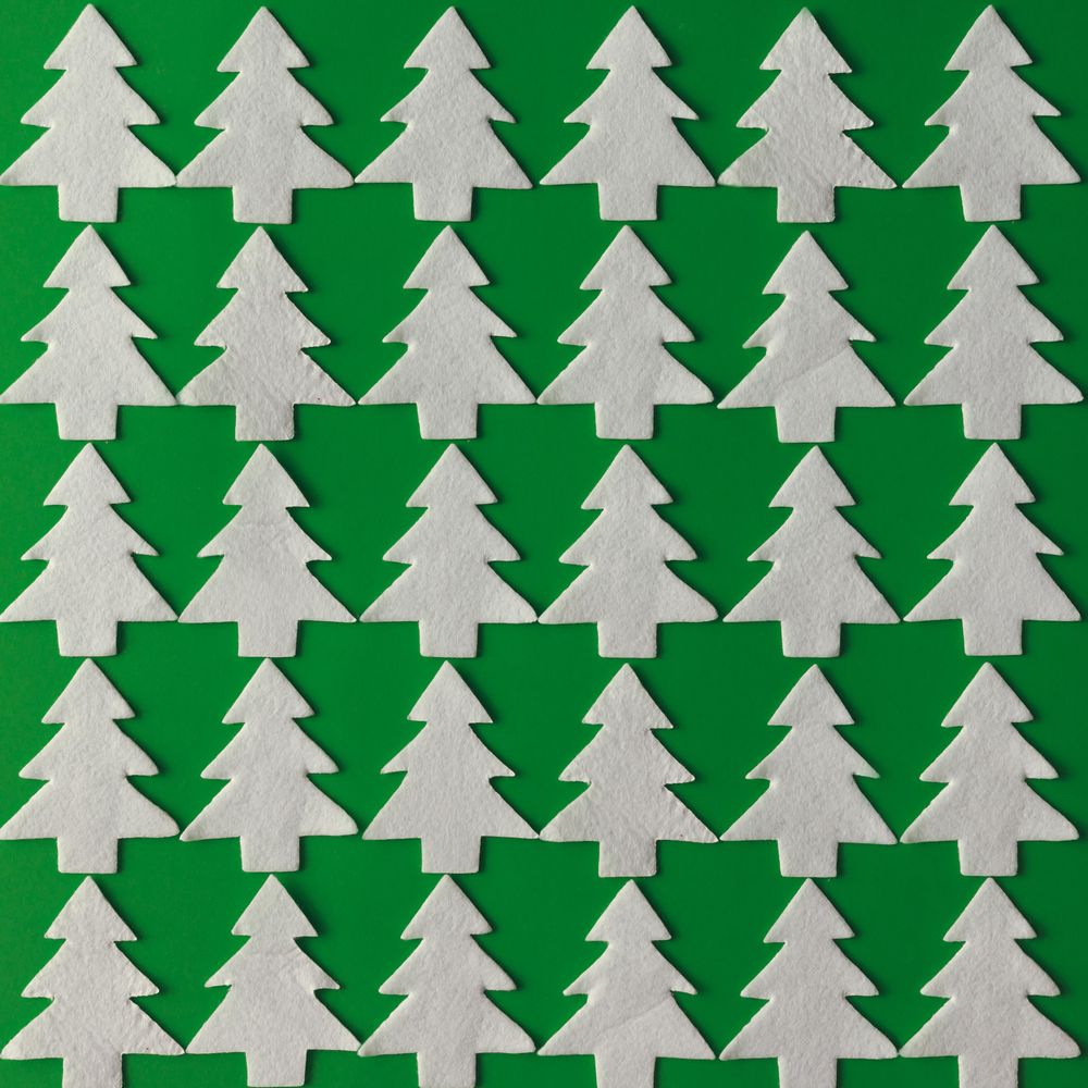 Pattern made of felt Christmas trees on green background