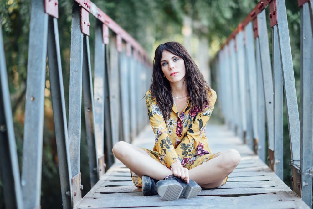 Female sitting cross legged on a rural bridge