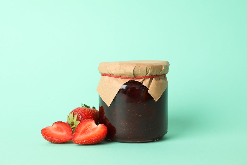 Delicious strawberry jam on mint background, space for text